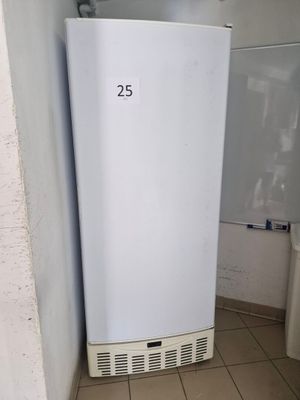 a white refrigerator in the corner of a bathroom