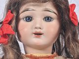 a close up of a doll with a red bow on it ' s head