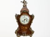 a clock that is sitting on a stand on a white surface
