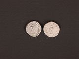two silver coins are shown on a black surface
