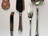 many different types of silverware on a white table