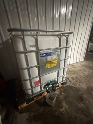 un grand conteneur blanc posé sur une palette dans un garage