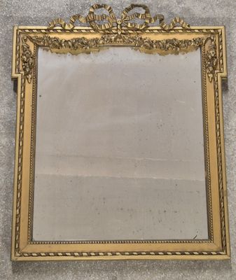 un miroir à cadre doré posé au sol, près d'un mur