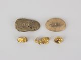 three gold nuggies and a rock on a white surface