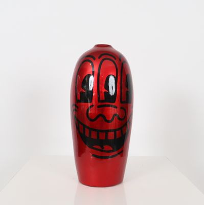 a red vase with a face painted on it