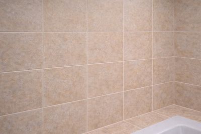 une baignoire dans une salle de bains carrelée équipée d'une pomme de douche