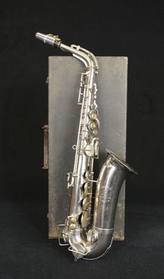 un vieux saxophone en argent avec un étui en argent sur fond noir