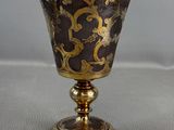 gold and black goblet sitting on top of a white table