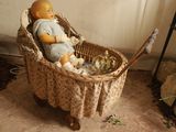une poupée assise dans un panier contenant une peluche