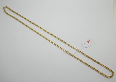 une paire de chaînes en or posées sur une surface blanche