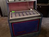 un juke-box bleu et rouge posé sur le sol d'un garage