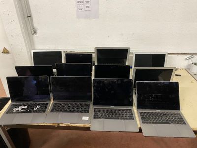 Plusieurs ordinateurs portables sont alignés sur une table devant un mur.