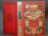 an old book with a red cover sitting on top of a table
