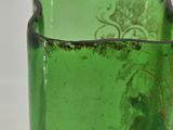a green glass vase that is sitting on a table