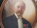 portrait d'un homme en costume-cravate tenant une photo encadrée de lui-même