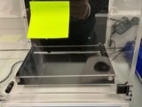 a man standing in front of a machine with a sticky note on it