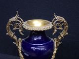 a blue vase with a gold handle on a black surface