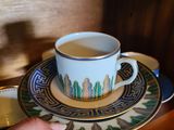 une personne tenant une tasse et une soucoupe posées sur une assiette