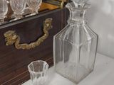 bottles and glasses on a table in front of a chest of drawers
