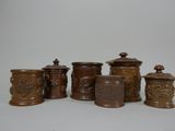 cinq vases marron posés sur une table, sur fond blanc