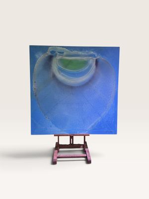un petit chevalet sur lequel est posé un tableau, posé sur une surface blanche