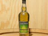 une bouteille de Chartreuse posée sur un tonneau
