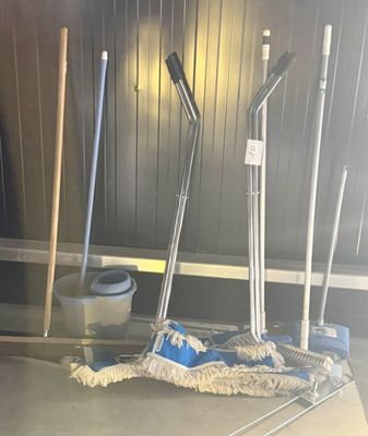 a mop, bucket, and broom on the floor in a room