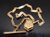 une chaîne en or sur laquelle sont accrochés un cadenas et un stylo