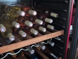 many bottles of wine in a wine cooler in a kitchen