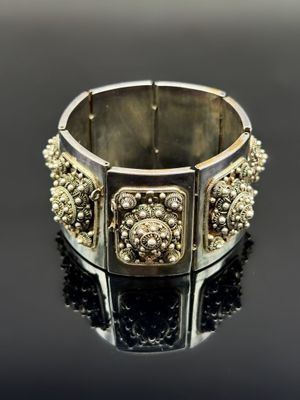 gros plan d'un bracelet en argent sur une surface noire