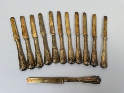 six antique silverwares and a knife on a white surface