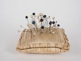 a pin holder with pins and pearls on it