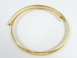 a close up of a gold bang bracelet on a white surface