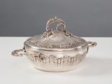 une cocotte en métal argenté munie de poignées, posée sur une table