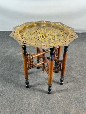 une table-plateau ancienne en laiton, avec des pieds en bois et un plateau en métal posé dessus
