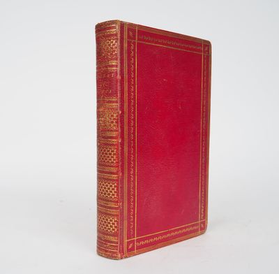 an old red book sitting on top of a white surface