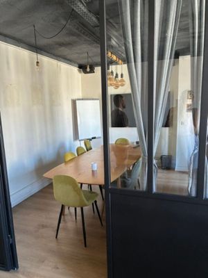 une pièce avec une table, des chaises et un miroir accroché au mur