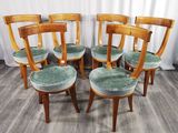 six chaises en bois avec des assises rembourrées vertes, devant un rideau blanc