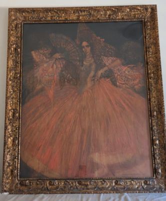 tableau représentant une femme en robe rouge, dans un cadre doré, posé sur une table