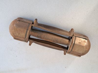un petit objet en bronze posé sur une surface blanche