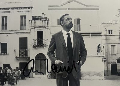 photographie en noir et blanc d'un homme en costume-cravate, debout devant un immeuble