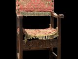 an old wooden chair with a red and gold upholstered seat