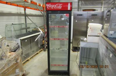 a coca cola cooler in the middle of a warehouse