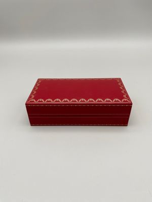 une petite boîte rouge avec des bordures dorées sur les côtés