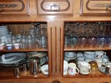 many cups and saucers on the shelves of this cabinet