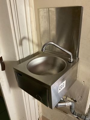 a stainless steel sink in the corner of a bathroom