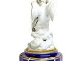 a statue of an angel sitting on a blue pedestal