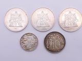 a group of five silver coins sitting on top of a white surface