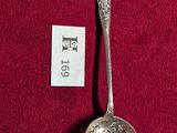 une cuillère en argent posée sur une nappe rouge, avec une étiquette accrochée dessus