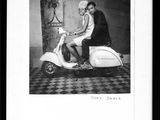 black and white photograph of a woman sitting on a motor scooter